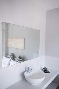 Baño blanco con lavabo y espejo en Akra Morea Hotel & Residences, en Monemvasia