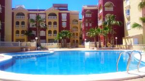 a large swimming pool in front of some buildings at Beautiful 3 bed, 2 bath modern apartment in Los Alcázares