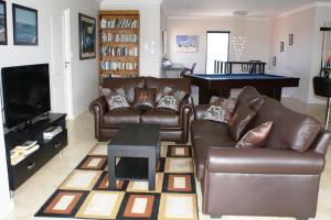 sala de estar con sofás de cuero y TV en Le Marina B&B, en Velddrif