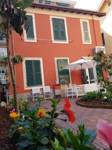an orange house with chairs and an umbrella at Villetta Volta in Rapallo