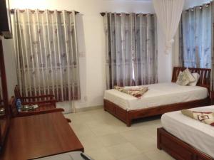 1 dormitorio con 2 camas, mesa y sillas en Nhat Quang Bungalow, en Mui Ne