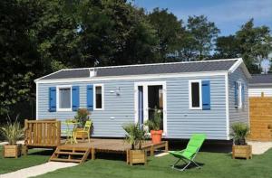 a blue tiny house with a deck and chairs at Camping Au Bord de l'Aisne in Guignicourt