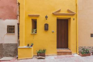um edifício amarelo com uma porta e vasos de plantas em B&B Alla Cattedrale em Agrigento