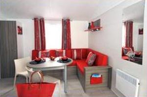 a living room with a red couch and a table at Camping Au Bord de l'Aisne in Guignicourt