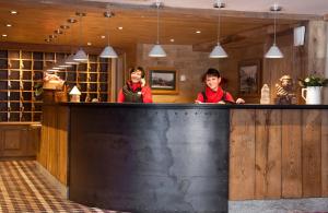 two women standing behind a bar in a restaurant at Chalet-Hôtel La Marmotte, La Tapiaz & SPA, The Originals Relais (Hotel-Chalet de Tradition) in Les Gets