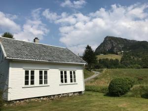 a white house with a mountain in the background at Høiland Gard Gardshotellet in Årdal