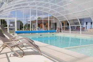 a swimming pool with a chair in front of a building at Camping Au Bord de l'Aisne in Guignicourt