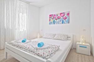 a white bedroom with a bed with blue towels on it at Apartments Punta by Sea in Umag