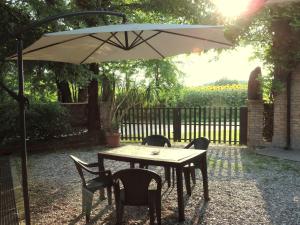 una mesa con sillas y una sombrilla en un patio en B&B I Prati di Varmo, en Romans di Varmo