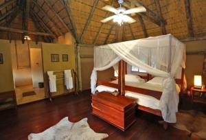 ein Schlafzimmer mit einem Himmelbett und einer Decke in der Unterkunft Camp Kwando in Kongola