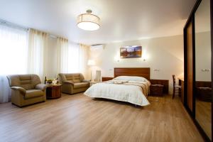 a bedroom with a bed and a couch and chairs at APART-HOTEL VEGUS in Uralsk