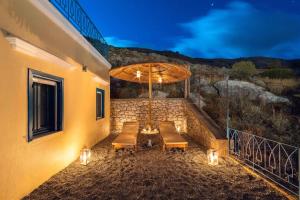 a patio with a table with an umbrella and lights at Royal Villa Pedi in Symi