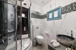 a bathroom with a tub and a sink and a toilet at Royal Villa Pedi in Symi