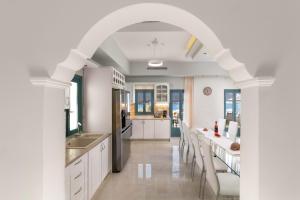 an archway in a kitchen with white cabinets and chairs at Royal Villa Pedi in Symi