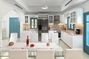 a kitchen with a white table and white chairs at Royal Villa Pedi in Symi