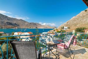 a balcony with a table and chairs and a view of the water at Royal Villa Pedi in Symi