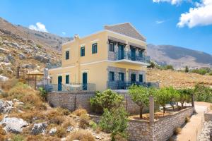 a large yellow house on top of a hill at Royal Villa Pedi in Symi