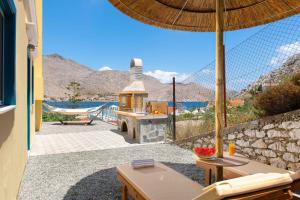 a patio with an outdoor grill and an umbrella at Royal Villa Pedi in Symi