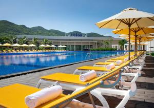 a row of yellow tables and umbrellas next to a swimming pool at Oceanami Villas & Beach Club - Managed by Thang Long Group in Long Hai
