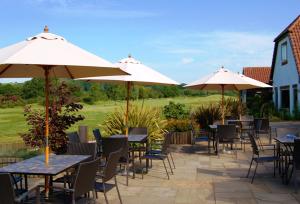 a patio with tables and chairs with umbrellas at Blacknest Golf and Country Club in Alton