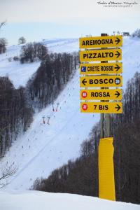 a pole with signs on a ski slope with skiers at Snowake House in Castel di Sangro