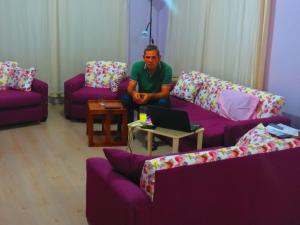 een man in een woonkamer met een laptop bij Karya Apartments in Koycegiz