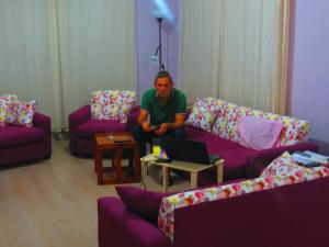 a man sitting in a living room with a laptop at Karya Apartments in Koycegiz