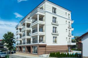 a white building with balconies on a street at Old Sailor Apartment in Obzor