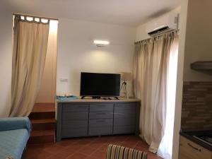 una sala de estar con TV en un tocador con cortinas en Casa Ginepro en Costa Paradiso