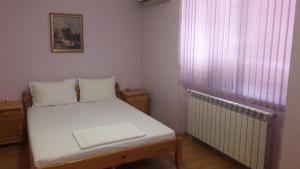 a small bedroom with a white bed and a window at Fenerite Family Hotel in Targovishte