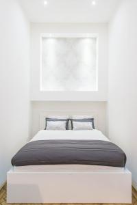 uma cama num quarto branco com uma fotografia por cima em Dominik Apartment em Budapeste