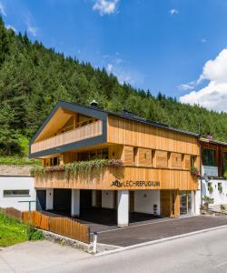 un bâtiment en bois avec une montagne en arrière-plan dans l'établissement Erholungswelt Lechrefugium, à Steeg