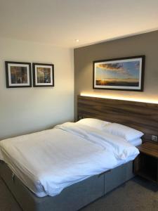 a bedroom with a large white bed and two pictures on the wall at Rivington Lodge in Bolton