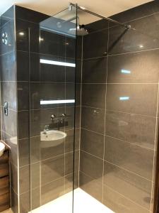 a bathroom with a glass shower with a sink at Rivington Lodge in Bolton