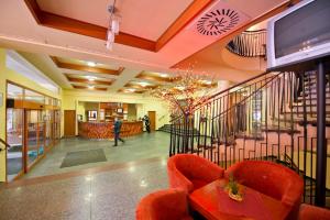 a lobby with orange chairs and a staircase at Hotel SOREA SNP in Belá