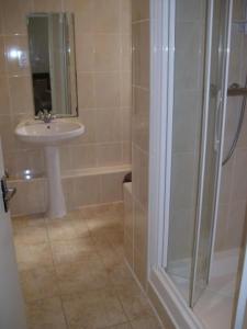 a bathroom with a shower, sink, and mirror at Barn Hotel London Ruislip in Hillingdon