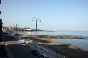 a street with cars parked on a road next to the ocean at The Glengower in Aberystwyth