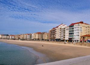 vistas a una playa con edificios y al océano en Apartamentos Vacacionales Caracas, en Sanxenxo