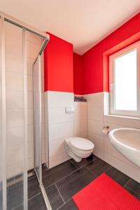 ゲーレンにあるVilla Mia Whg Nr 3 mit Terrasse EG 1 Raum Wohnungの赤い壁のバスルーム(トイレ、洗面台付)