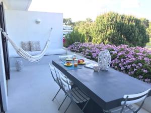 Soltroia Beachouse في ترويا: طاولة زرقاء وكراسي على فناء مع زهور أرجوانية
