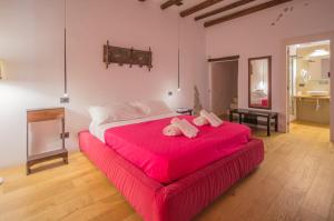 una camera da letto con un grande letto rosso con lenzuola rosa di Antichi Ricordi a Caltanissetta