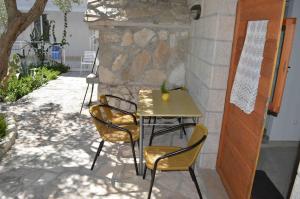 a table and chairs sitting next to a stone wall at Apartments Majstrovic in Živogošće