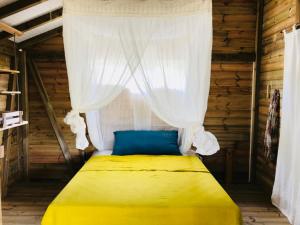 a bedroom with a yellow bed with a curtain at Bungalow de charme vue mer in Beauséjour