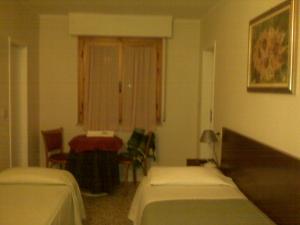 a room with two beds and a table and a table at Hotel Signorini in Castiglioncello