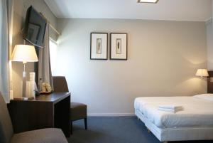a hotel room with a bed and a desk and a television at Fletcher Hotel Restaurant Bon Repos in Noorbeek