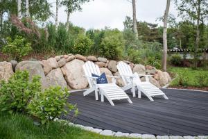 two white chairs sitting on a deck next to a rock wall at Kapitaensweg 12 in Ostseebad Karlshagen