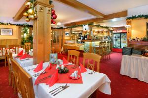 Um restaurante com mesas brancas e guardanapos vermelhos. em Hotel Spindlerova Bouda em Špindlerŭv Mlýn