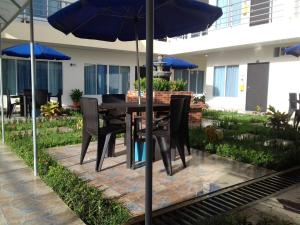 een tafel met stoelen en een parasol op een patio bij Hotel la fuente j.n in La Macarena