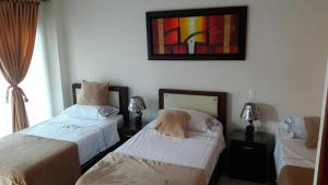 Habitación con 2 camas y una pintura en la pared. en Hotel la fuente j.n, en La Macarena