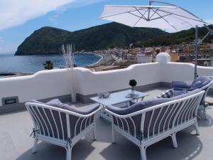 um pátio com cadeiras, uma mesa e um guarda-sol em Pietra Pomice Hotel em Canneto